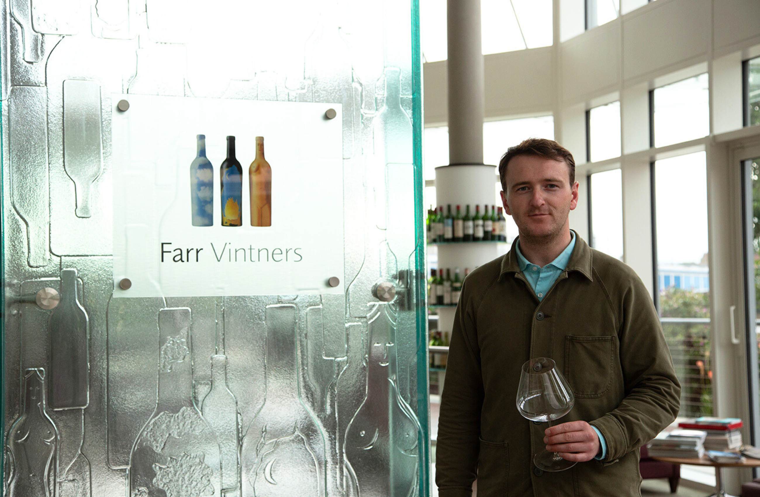 Patrick from Farr Vintners posing with a wine glass at the entrance to their offices in Battersea
