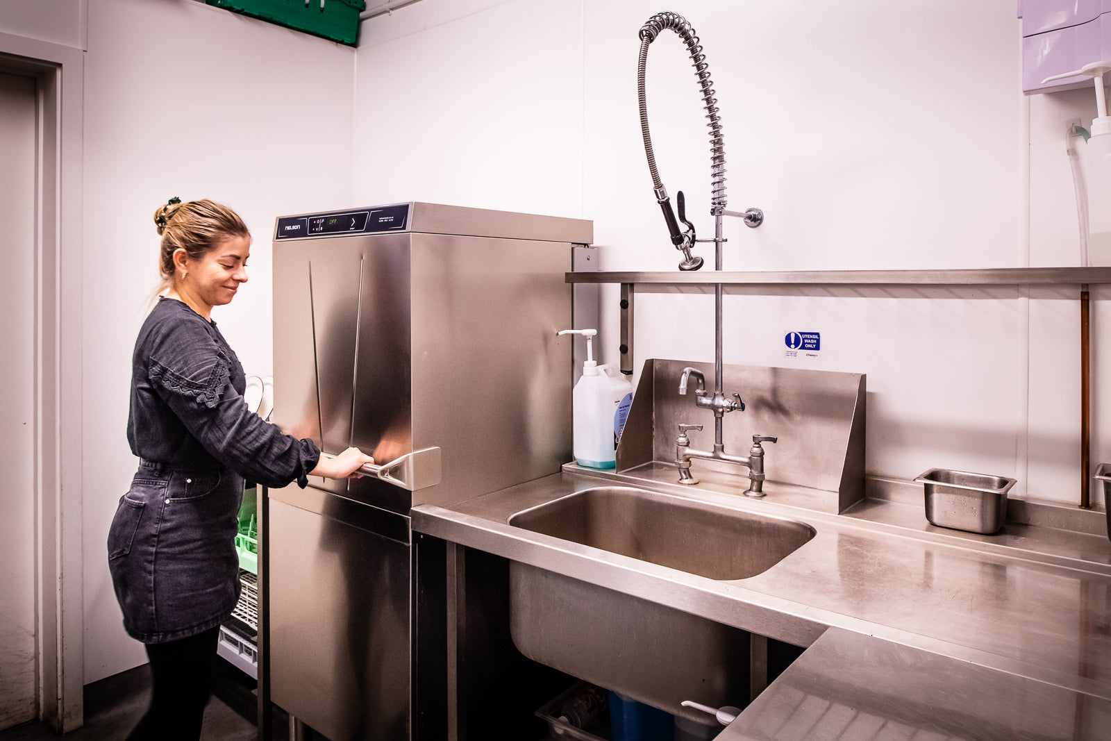 Operator using a Nelson AD55 Passthrough Commercial Dishwasher